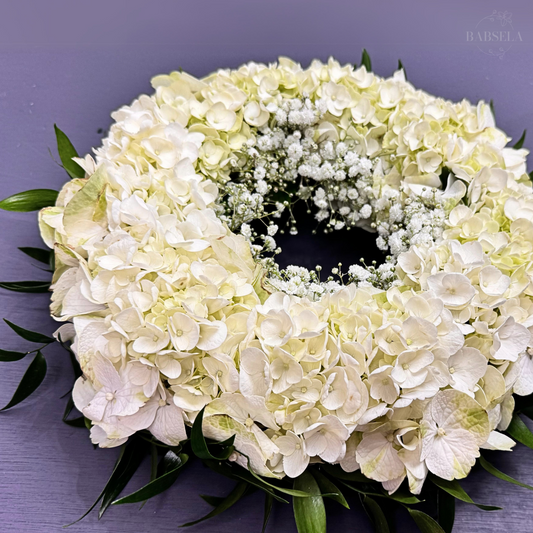 Angelic Wreath from Babsela Florist Beckenham, featuring white hydrangeas and greenery. Available for same-day and free local delivery