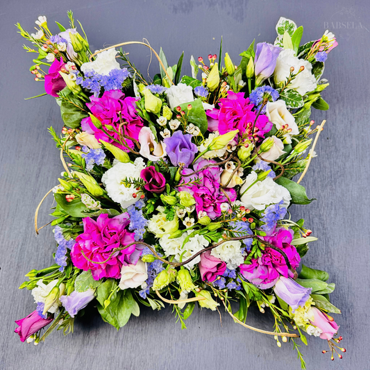 Square-shaped floral arrangement with vibrant pink, purple, white, and blue flowers, featuring a mix of roses, lisianthus, and greenery by Babsela