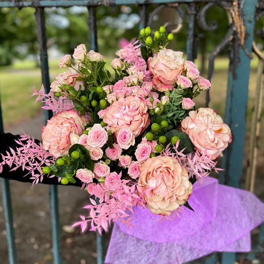 A person holds a vibrant bouquet of pink flowers, showcasing their delicate petals and lush greenery.